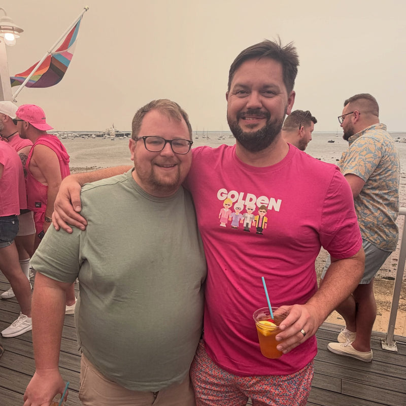 Two friends at a tea dance, one in the pink Golden Gals tee