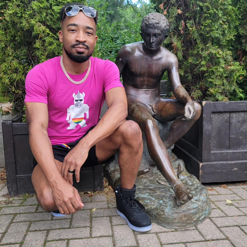A man in a pink Uno the Unicorn tee beside a bronze statue