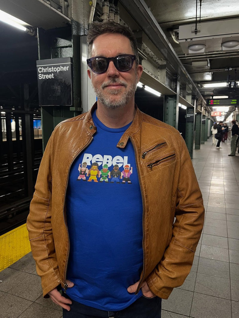 A man on a subway platform in the Rebel tee under a leather jacket