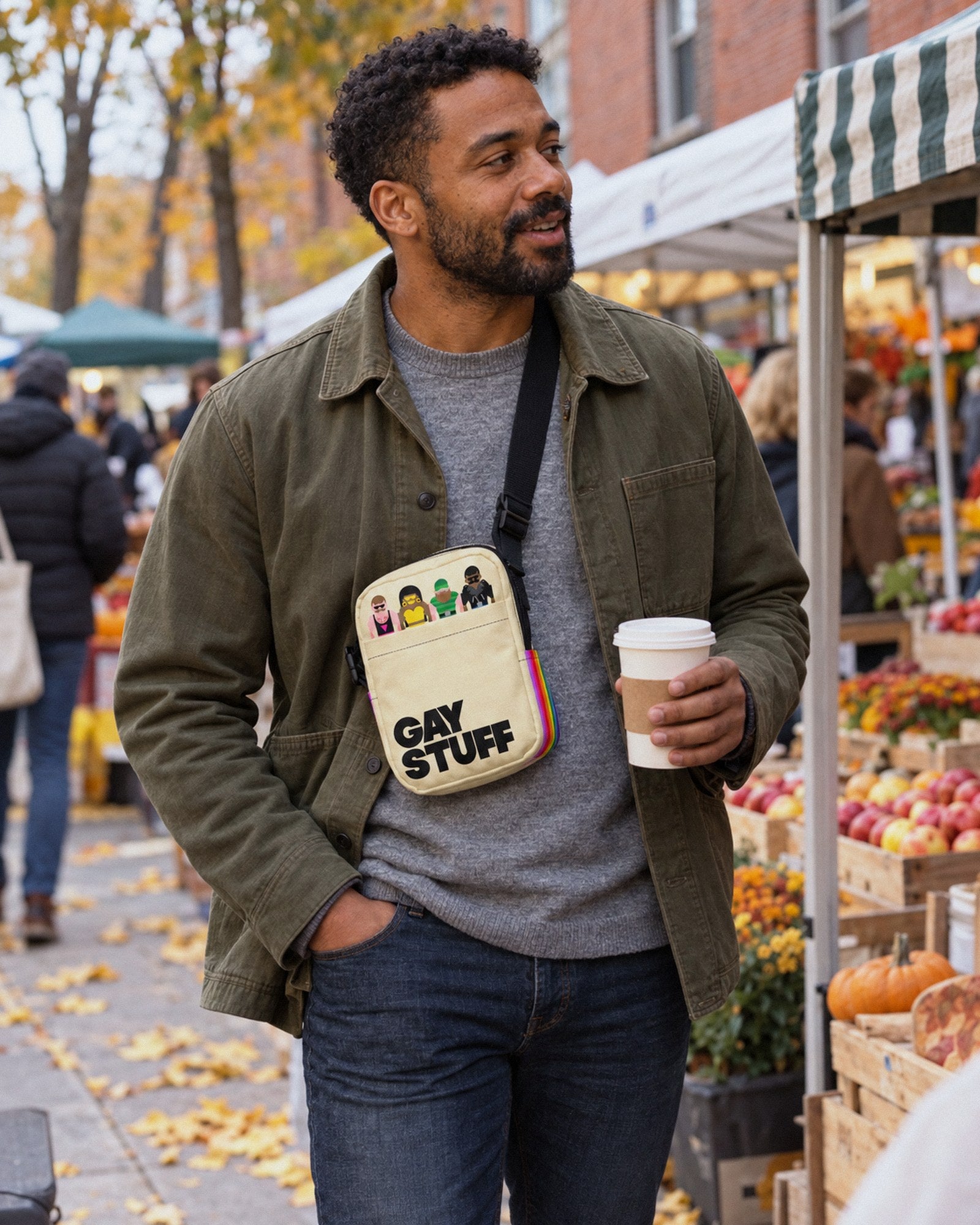 A mate at an outdoor fall market with the Gay Stuff Crossbody Bag across his chest and a coffee in hand